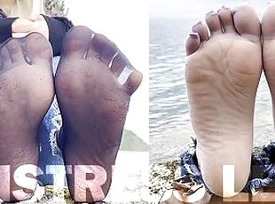 Feet tease in black and grey nylon socks wiggling toes at the seashore