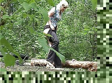 Cute blonde pissing on a long in the woods