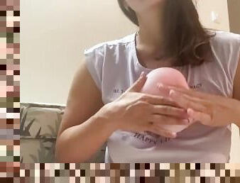 Woman plays with small pink balloon (the balloon doesn't burst)